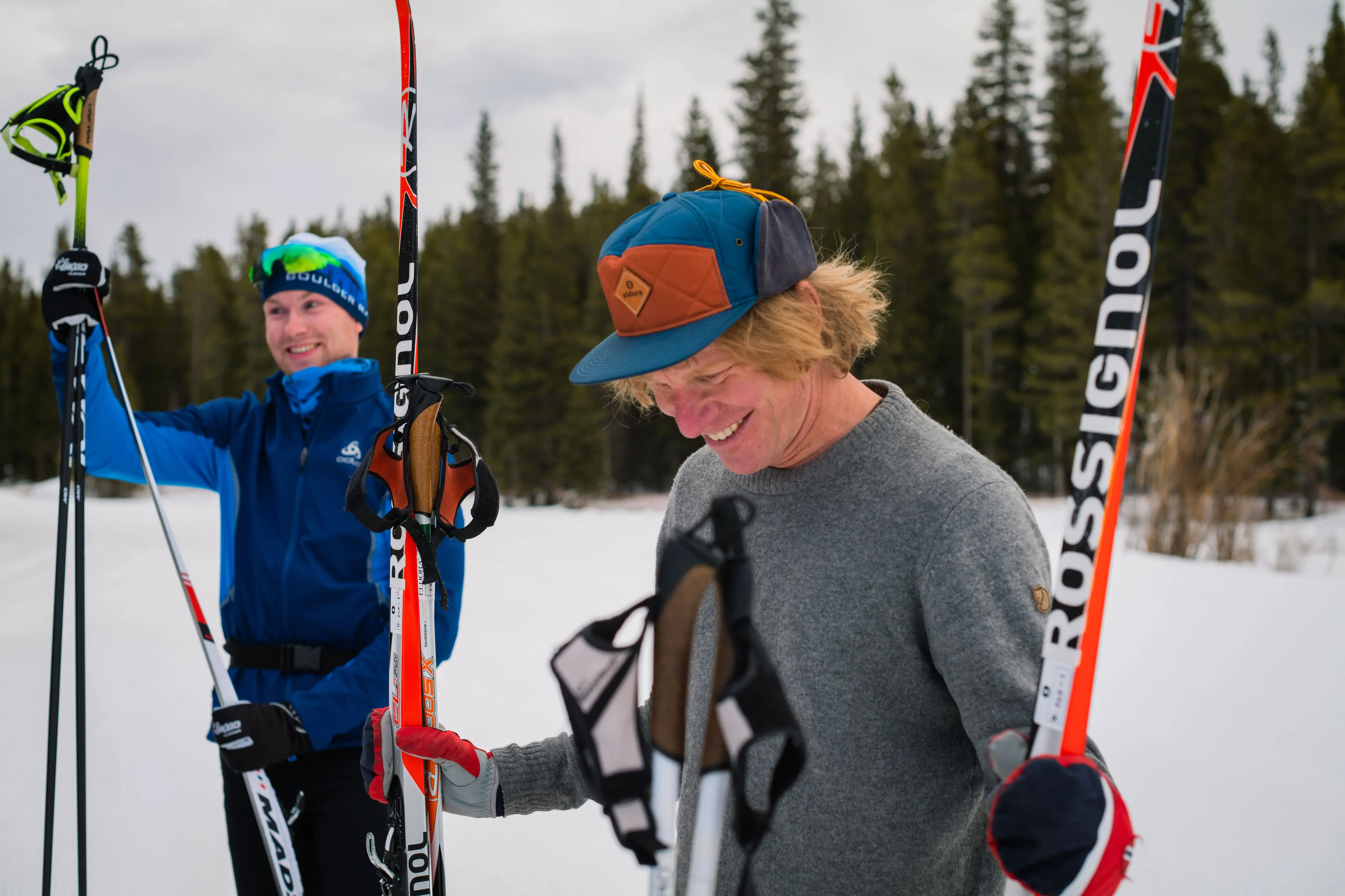 two men smile and hold nordic skis