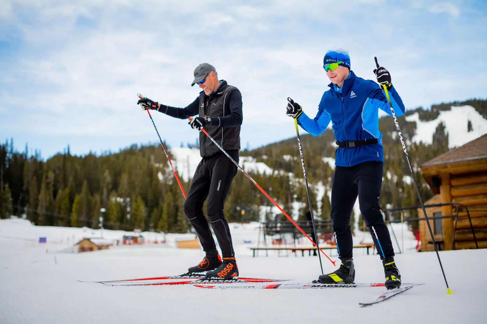 two men stand in front of the nordic center preparing to go ski