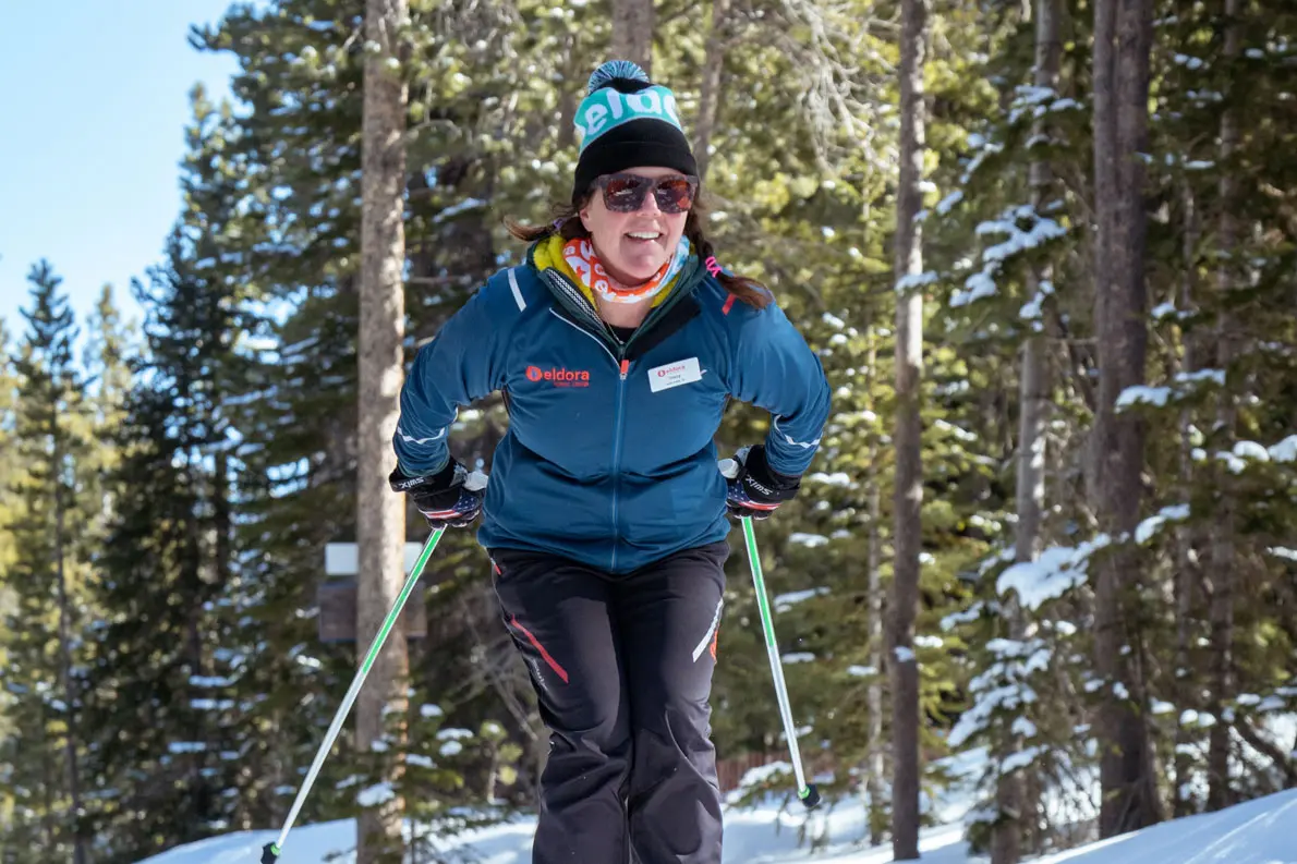 woman skis by the camera, smiles