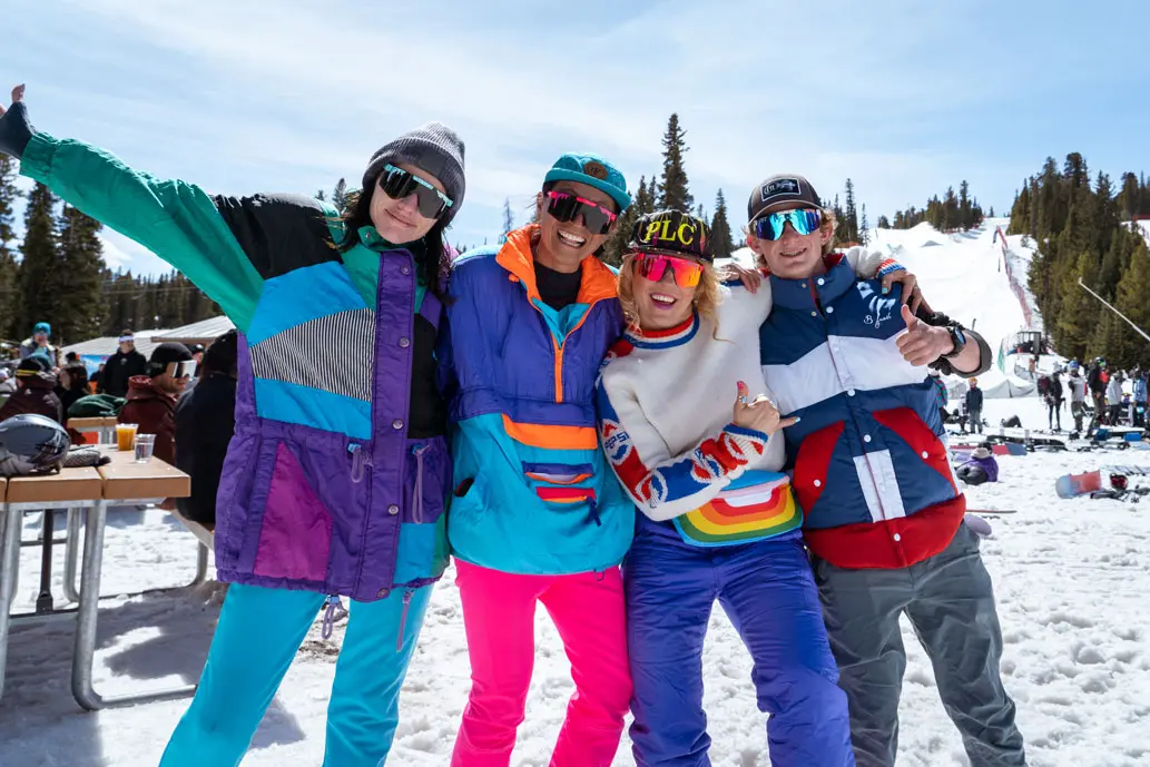 group of 4 people dressed in retro gear smiles at the camera