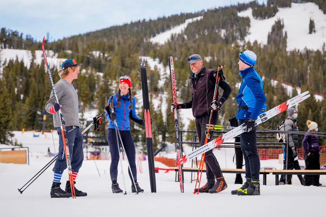 nordic skiers stand and smile at each other