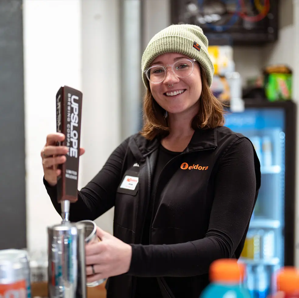 woman smiles at camera while she pours a beer
