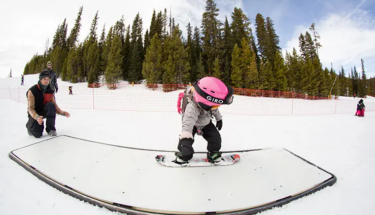 kid in pink helmet slides on a box