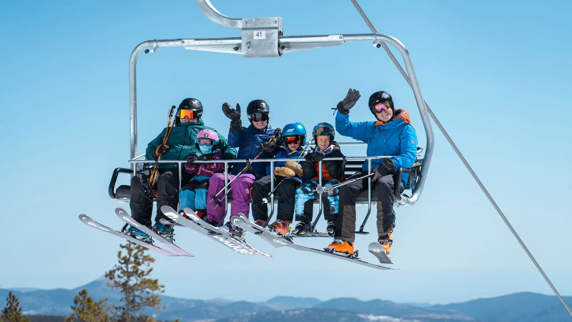 family on chairlift waves at the camera